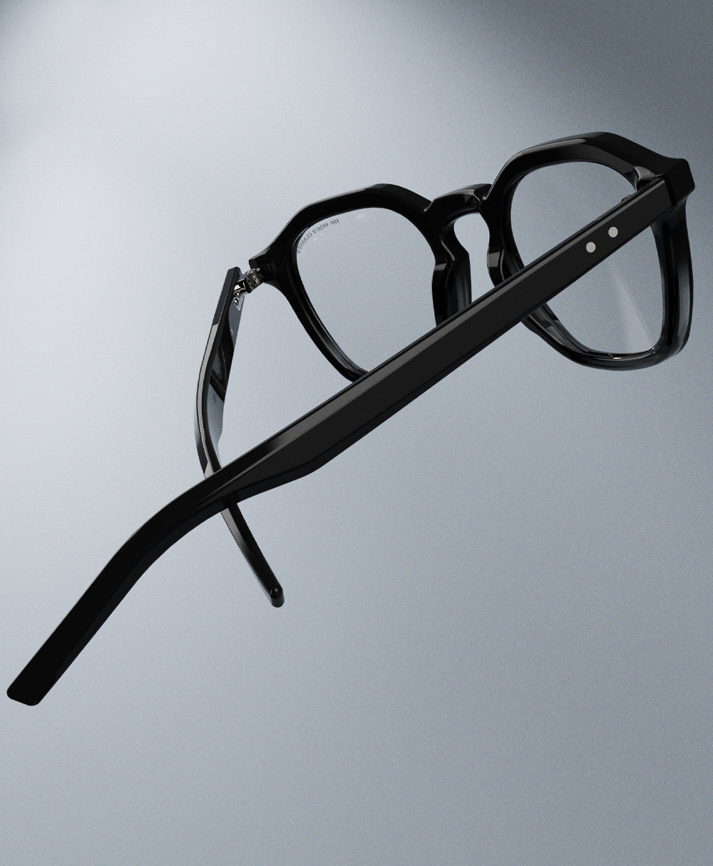 Black eyeglasses on a reflective gray surface